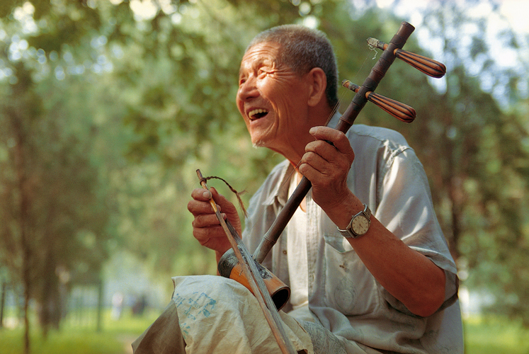 Au matin dans le parc Tiantan,  Pkin, Zhang Yinsheng se dtend en jouant de l<i>erhu</i>, violon dont larchet est toujours coinc entre les deux cordes (Chine).